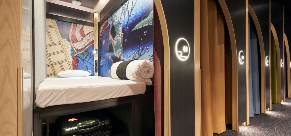 The single cabin at Resol Poshtel Tokyo Asakusa showing the bed and storage under with suitcase