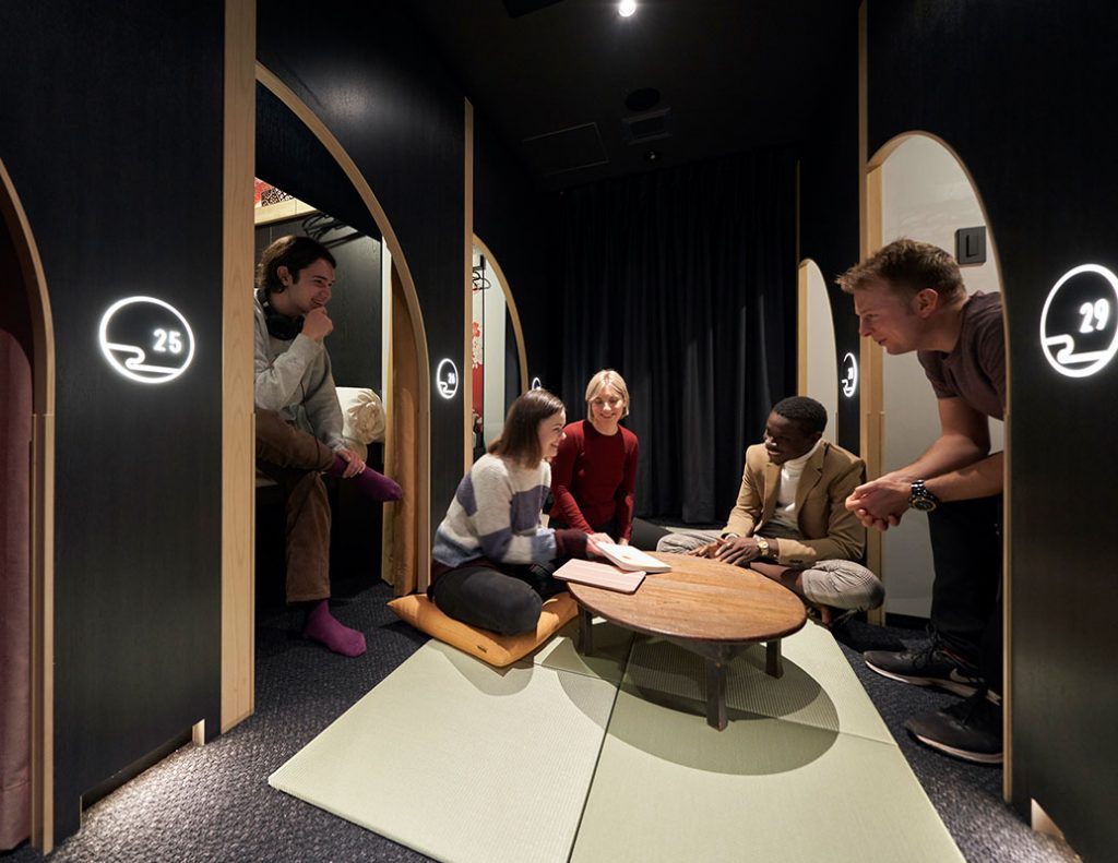 The private pod blocks at Resol Poshtel Tokyo Asakusa with 6 capsules facing eachother with a table in the middle