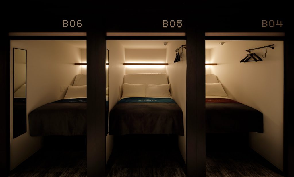 Capsules with the bed raised up in seating position and dimmed lights showing The Millennials Shibuya wake-up alarm system
